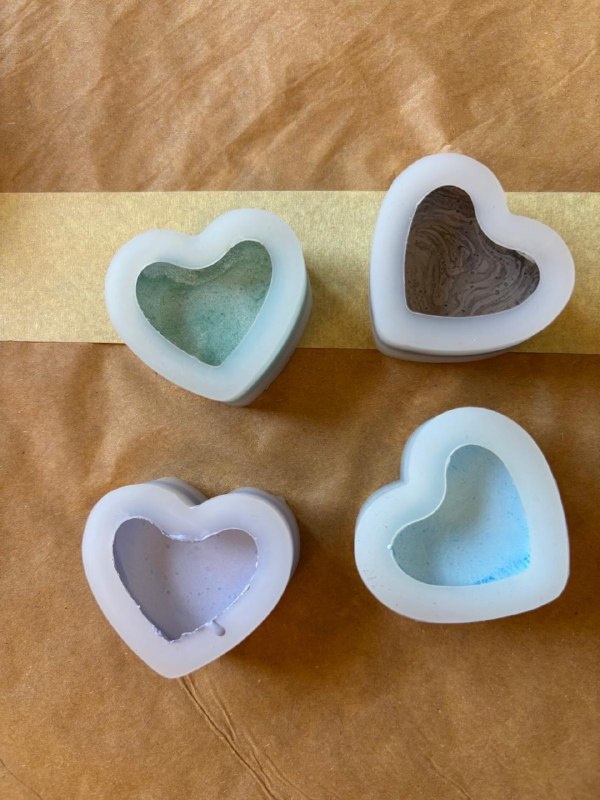 Quattro creazioni a cuore in gesso con sfumature verde, marrone, rosa e azzurro